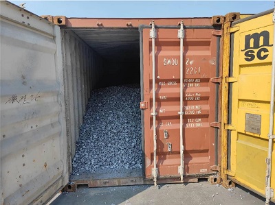 Bulk metallic grey low aluminum ferro silicon lumps loaded directly on container floor with container door open showing shipping info for Australia